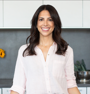 A smiling woman wearing a necklace, showcasing a joyful expression, relevant to WeNatal's focus on health and wellness products for families.